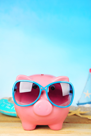 Piggy bank with sunglasses on wooden table, outdoorsの写真素材
