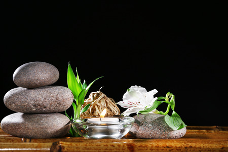 Beautiful composition with spa stones and candle on table on dark background