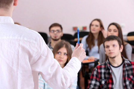 Group of students sitting in classroom and  listening teacher