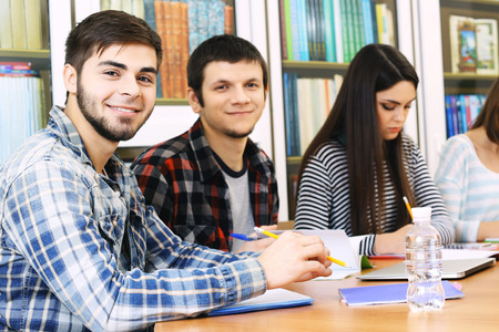 Group of students sitting at table in libraryの写真素材