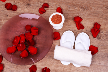 Spa bowl with water, rose petals, towel and slippers on light background. Concept of pedicure or natural spa treatmentの写真素材