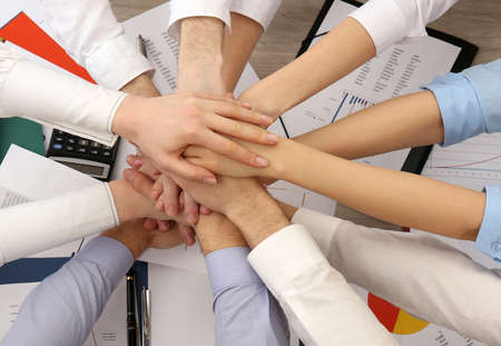 United hands of business team on workspace background, top viewの写真素材