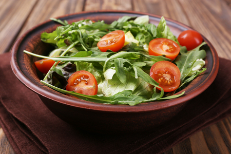Salad with arugula and cherry tomatoes on wooden tableの写真素材