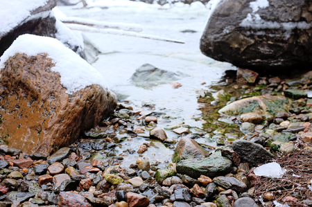 Stones in river covered with snowの写真素材