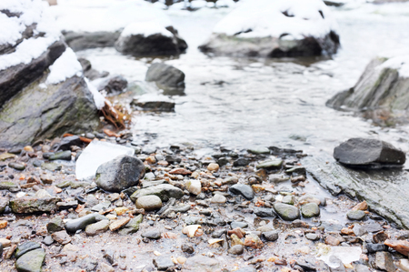Stones in river covered with snowの写真素材
