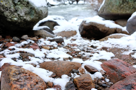 Stones in river covered with snowの写真素材