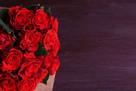 Bouquet of red roses wrapped in paper on wooden backgroundの写真素材