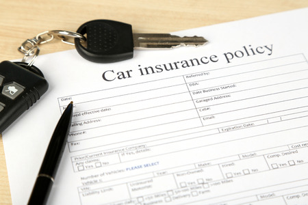 Car keys on insurance documents, close up