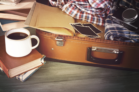 Vintage suitcase open with clothes and books on wooden backgroundの写真素材