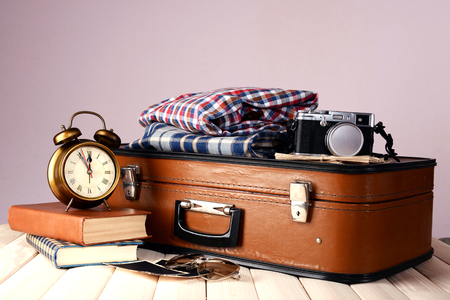 Vintage suitcase with clothes and books on table on dark colorful backgroundの写真素材