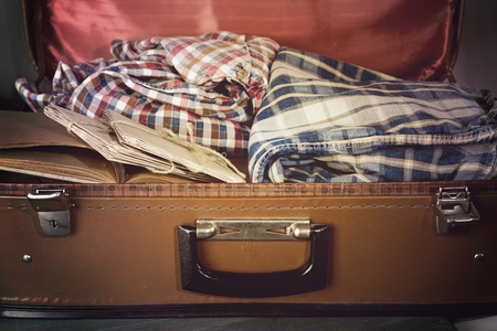 Vintage suitcase open with clothes and books close upの写真素材