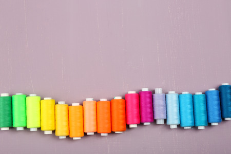 Multicolor sewing threads on wooden background
