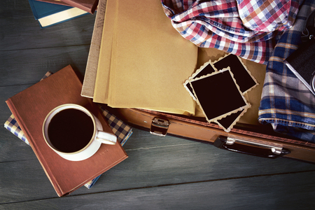 Vintage suitcase open with clothes and books on wooden backgroundの写真素材