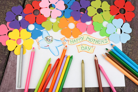 Happy Mothers Day message written on paper with pencils and decorative flowers on wooden backgroundの写真素材