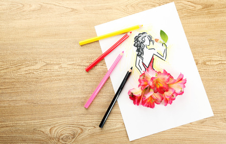 Picture with flower petals and pencils on wooden tableの写真素材