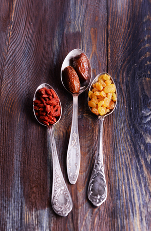 Dried fruits in silver spoons on rustic wooden table backgroundの写真素材