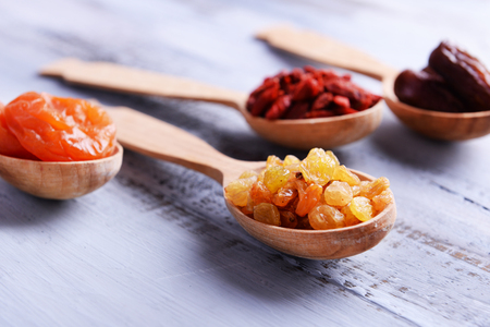 Dried fruits in spoons on color wooden table backgroundの写真素材