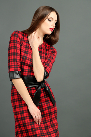 Beautiful young woman in squared dress on dark gray backgroundの写真素材