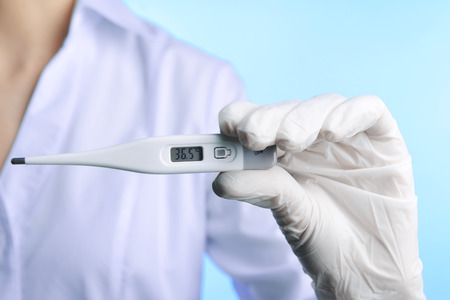 Doctor holding thermometer on blue background