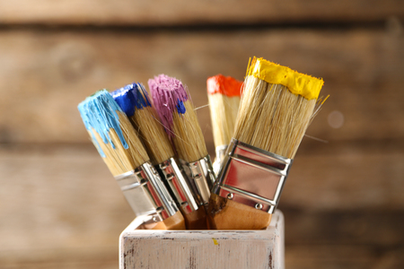 Brushes with colorful paints on old wooden backgroundの写真素材