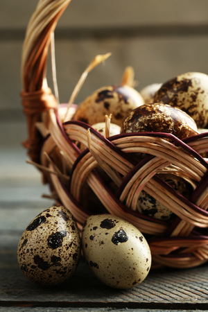 Bird eggs in wicker basket on wooden backgroundの写真素材