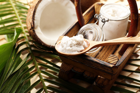 Jar of coconut oil with coconut and leaves on table close upの写真素材