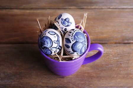 Easter eggs in mug on wooden background