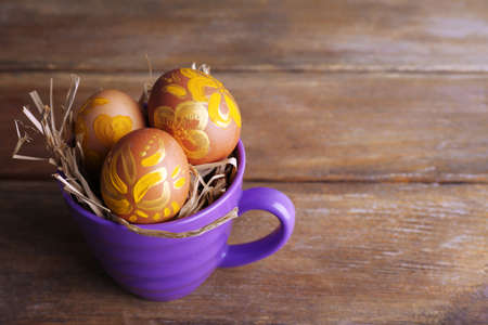 Easter eggs in mug on wooden background