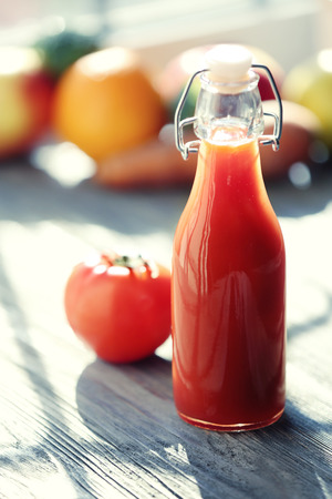 Bottle of tomato juice with fruits and vegetables on windowsillの写真素材