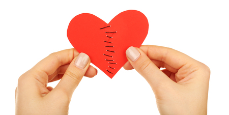 Female hands holding broken heart stitched from two pieces isolated on whiteの写真素材