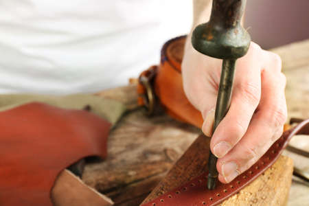 Repairing leather belt in workshop
