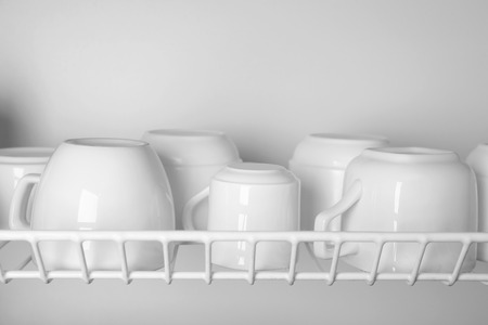 Clean cups drying on metal dish rack close upの写真素材