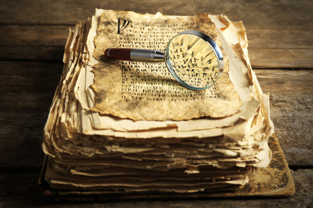 Grunge papers with hieroglyphics with magnifier on wooden backgroundの写真素材