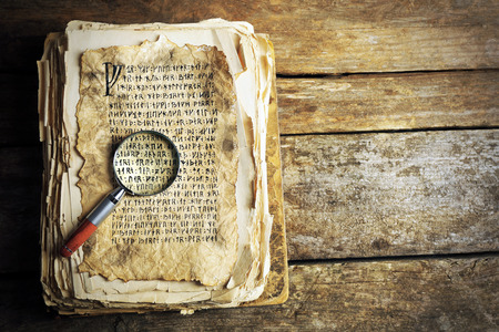 Grunge papers with hieroglyphics with magnifier on wooden backgroundの写真素材