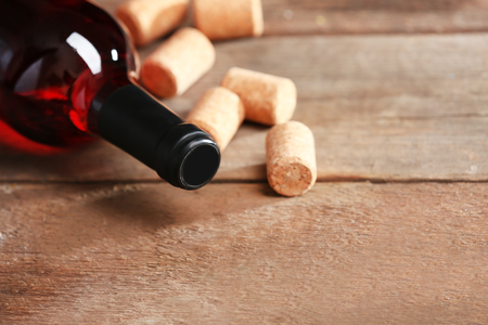 Glass bottle of wine with corks and corkscrew on wooden table backgroundの写真素材