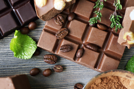 Set of chocolate with nuts, herbs and coffee beans on wooden table, closeupの写真素材