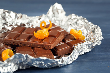 Chocolate with orange peels in foil on wooden table, closeupの写真素材