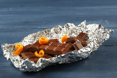 Chocolate with orange peels in foil on wooden backgroundの写真素材