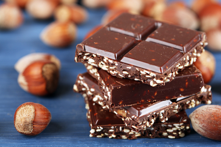 Pieces of chocolate with hazelnut on wooden table, closeupの写真素材