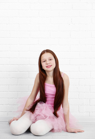 Beautiful little ballerina on  white bricks wall backgroundの写真素材