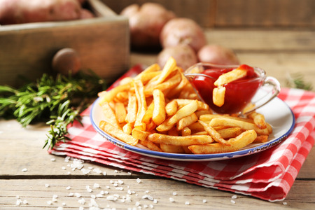 Tasty french fries on plate, on wooden table backgroundの写真素材