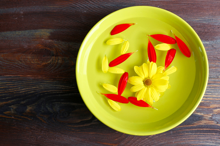 Flower petals in green bowl, close-up, on wooden table backgroundの写真素材