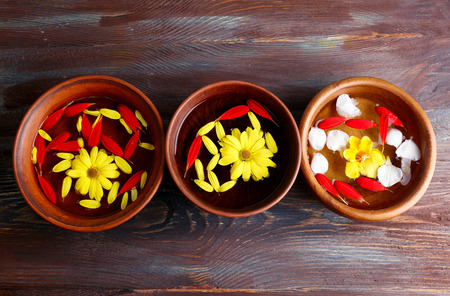 Flower petals in bowls, close-up, on wooden table backgroundの写真素材