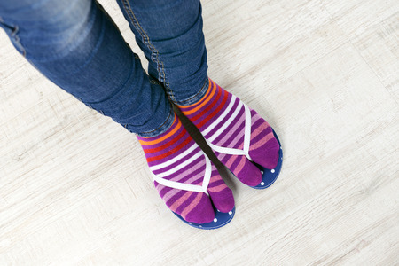 Female feet in socks with pink flip-flops, on floor background