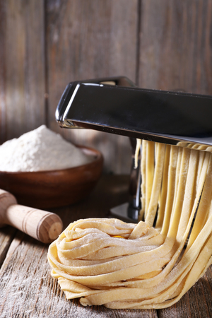 Making noodles with pasta machine on wooden backgroundの写真素材