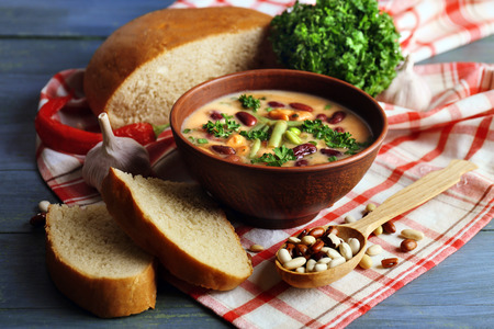 Bean soup in bowl with fresh sliced bread on napkin, on wooden table backgroundの写真素材