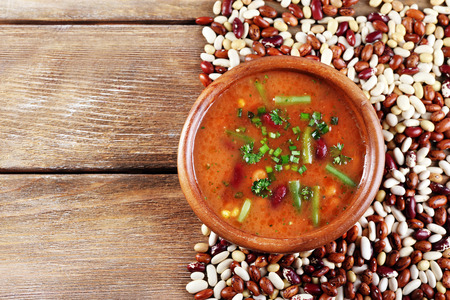 Bean soup in bowl and raw beans on wooden table backgroundの写真素材