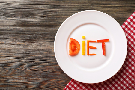 Word DIET made of sliced vegetables in white plate on wooden table, top viewの写真素材
