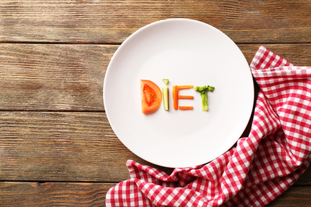 Word DIET made of sliced vegetables in white plate with napkin on wooden backgroundの写真素材