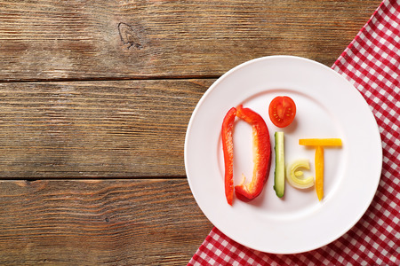Word DIET made of sliced vegetables in white plate on wooden table, top viewの写真素材